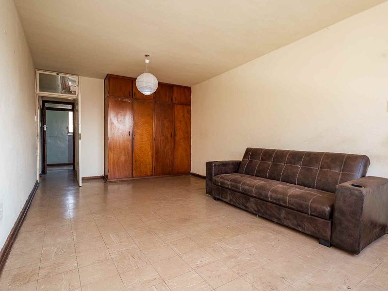 A living room featuring built-in wooden cupboards and tiled flooring, offering a functional space with potential for modernization and cosmetic updates.