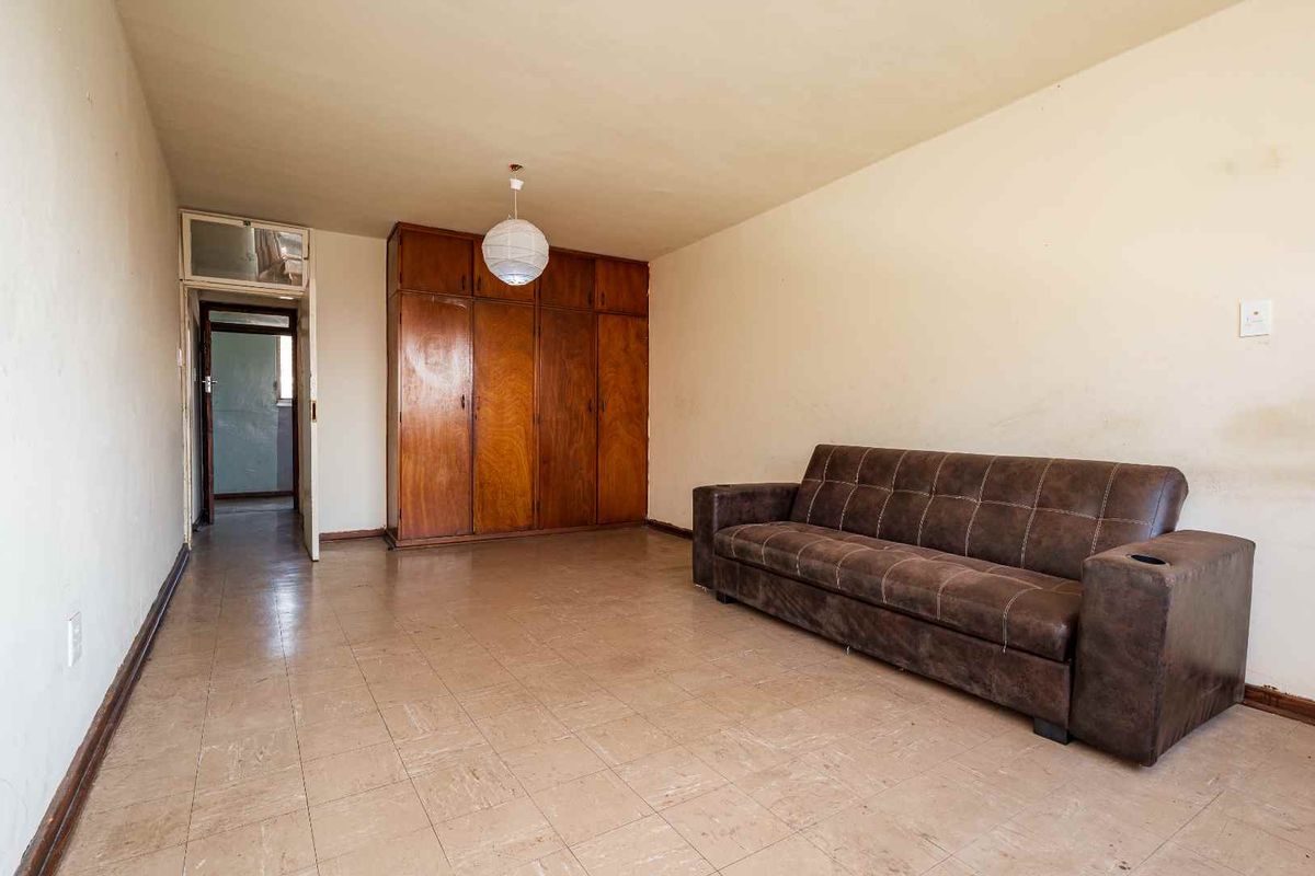 A living room featuring built-in wooden cupboards and tiled flooring, offering a functional space with potential for modernization and cosmetic updates.