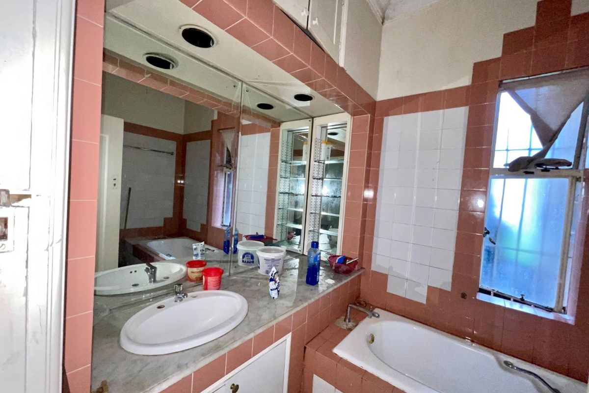 A vintage-style bathroom featuring pink and white wall tiles, a built-in vanity with a marble countertop, and a recessed bathtub.