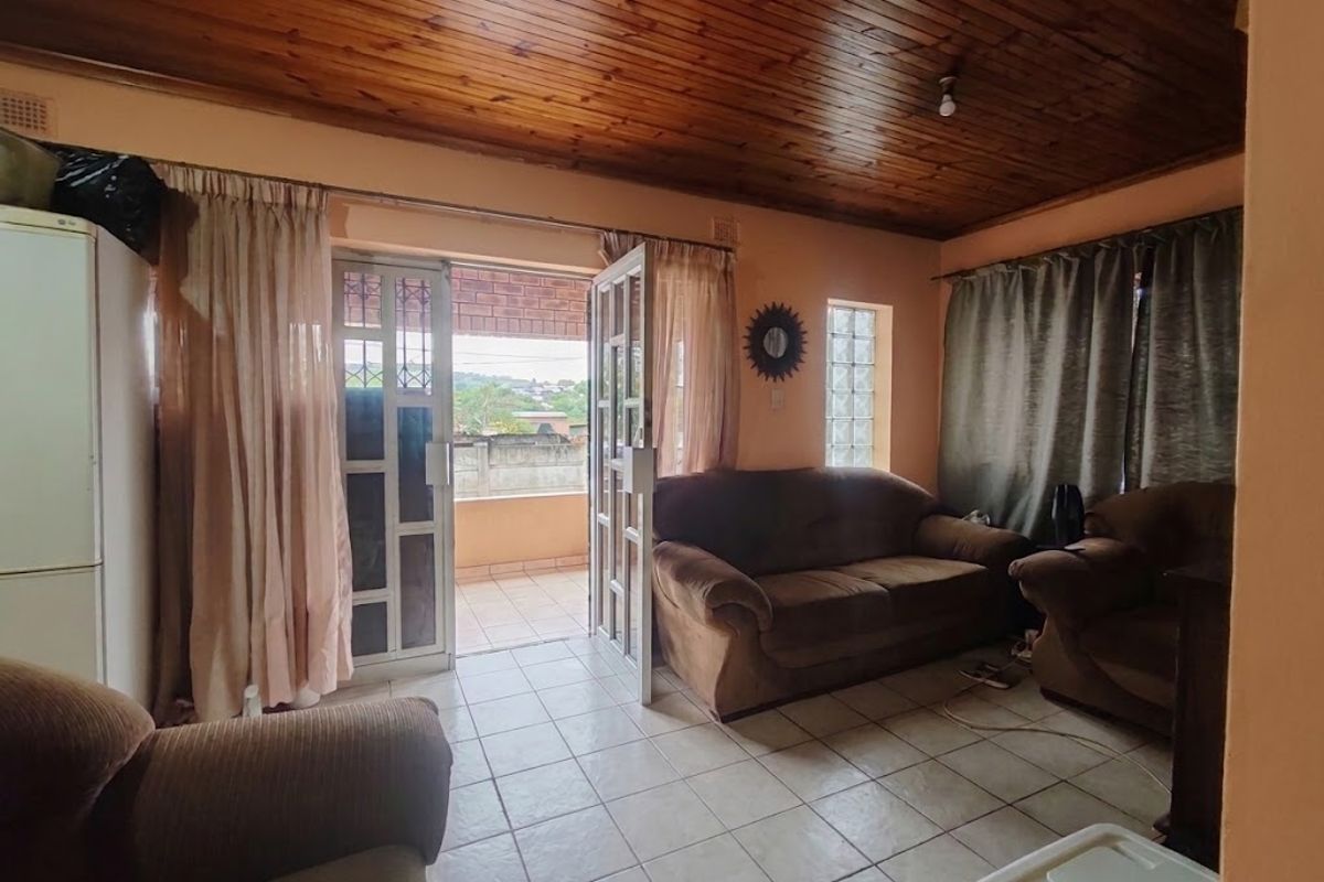 Living room featuring a timber tongue and groove ceiling, tiled flooring, and direct access to an outdoor patio area through glass doors.