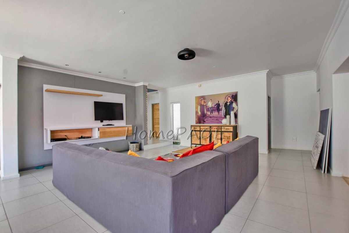 Spacious living room featuring neutral tiled flooring, recessed ceiling lighting, and a modern built-in media console unit.