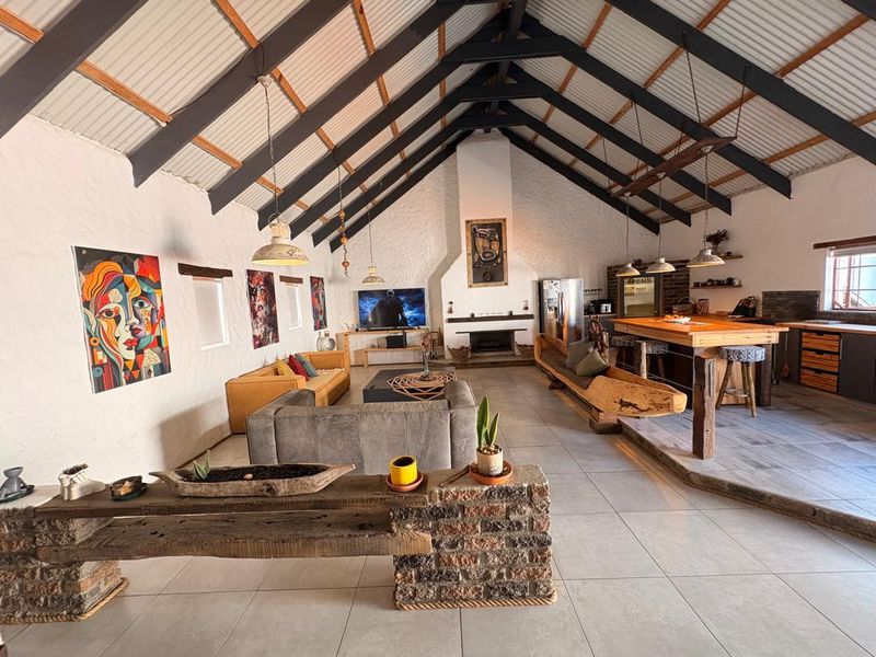 Spacious open-plan living area featuring a dramatic vaulted ceiling with exposed trusses, a central fireplace, and a large kitchen island with integrated cabinetry.