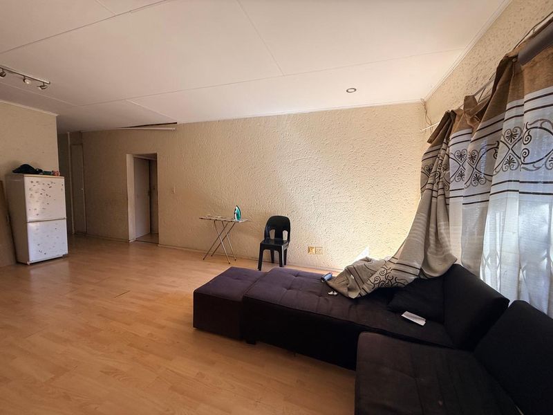 A spacious living area featuring laminate flooring, recessed downlighting, and textured wall finishes, offering a blank canvas for interior updates.