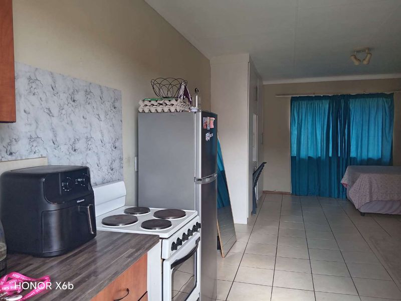 Open-plan kitchen and living area featuring tiled flooring, built-in cabinetry, and an electric stove, offering a functional layout for daily living.