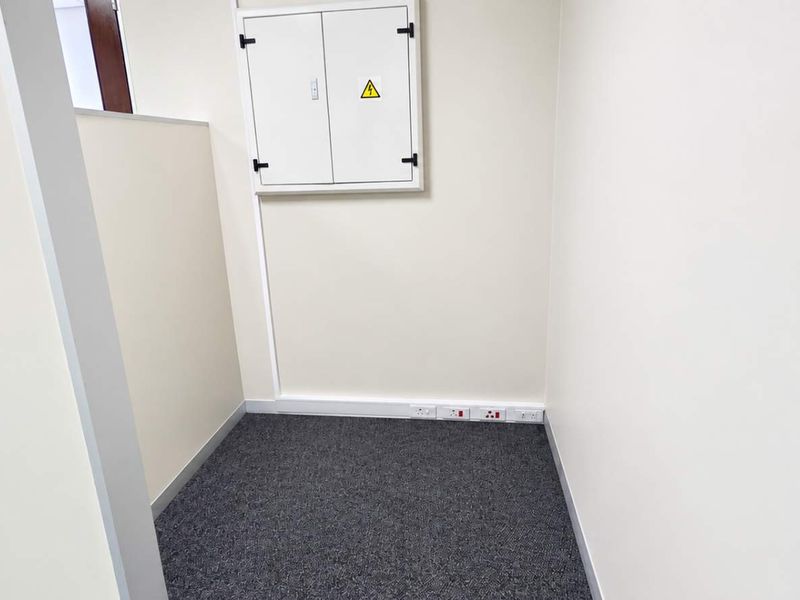 A clean, empty utility space featuring carpeted flooring, wall-mounted electrical distribution board, and multiple power outlets.