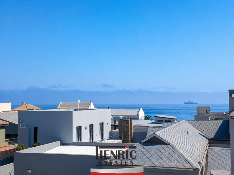 Elevated coastal view overlooking neighbouring rooftops towards the ocean horizon.