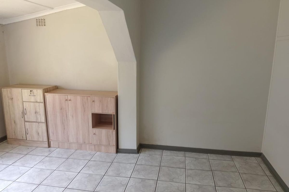 An empty living area featuring neutral tiled flooring, a structural archway, and simple wall finishes, providing a blank canvas for interior design.