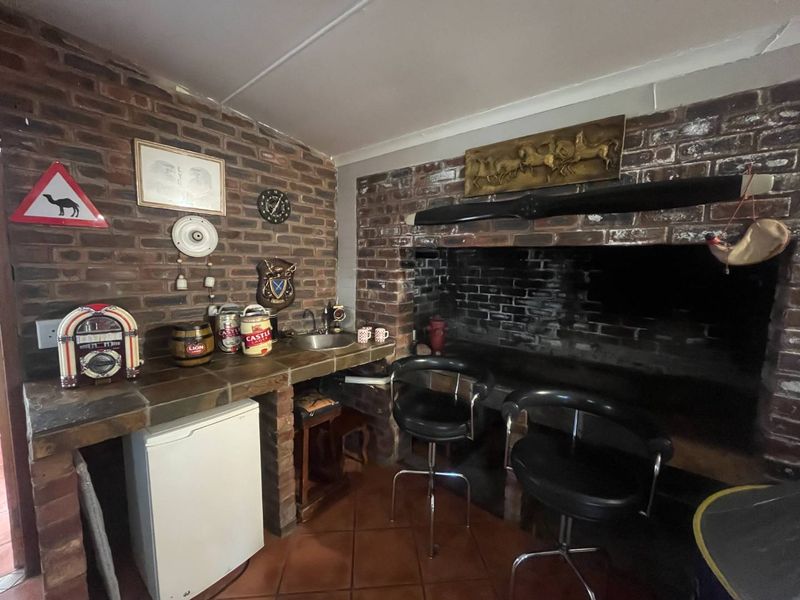A rustic bar area featuring a built-in brick fireplace, brick bar counter with integrated sink, and tiled flooring.
