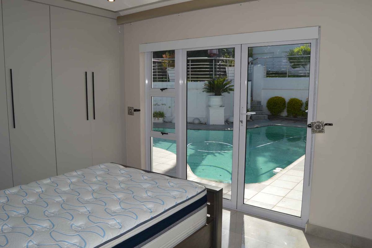 Bedroom featuring built-in cupboards, tiled flooring, and sliding glass doors providing direct access to the swimming pool area.