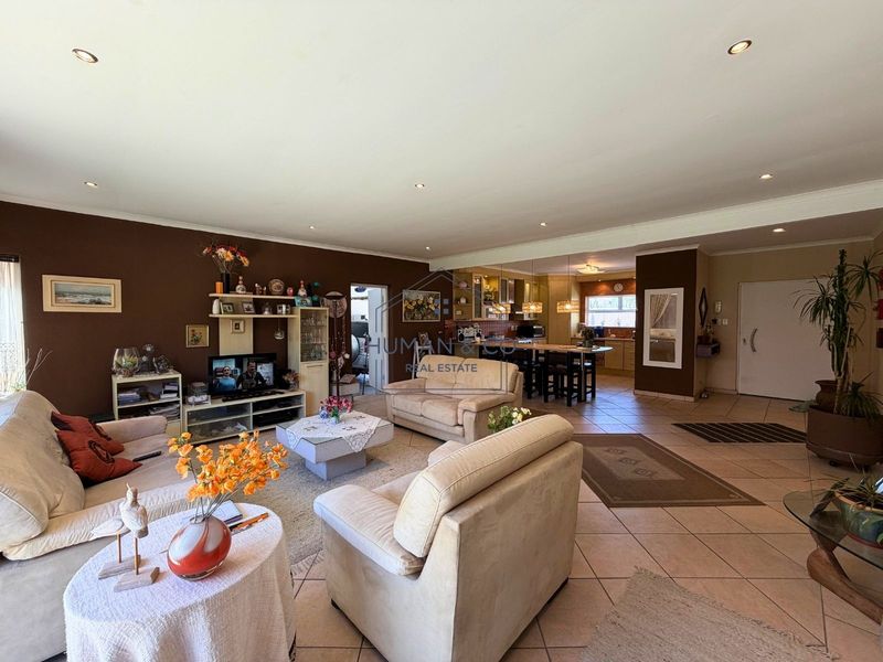 Spacious open-plan living area featuring tiled floors, recessed lighting, and a connected kitchen with a central island and built-in cabinetry.
