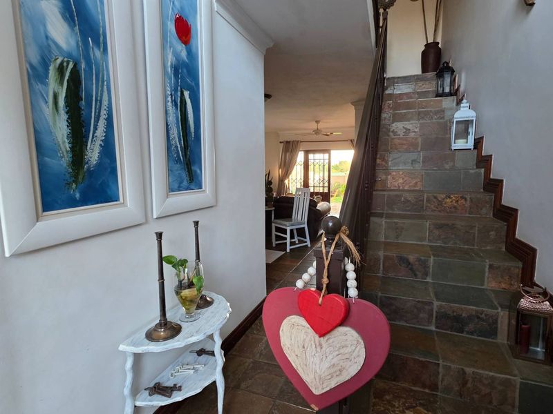 Entrance foyer featuring a stone-tiled staircase with a wooden handrail, leading through to the open-plan living area.