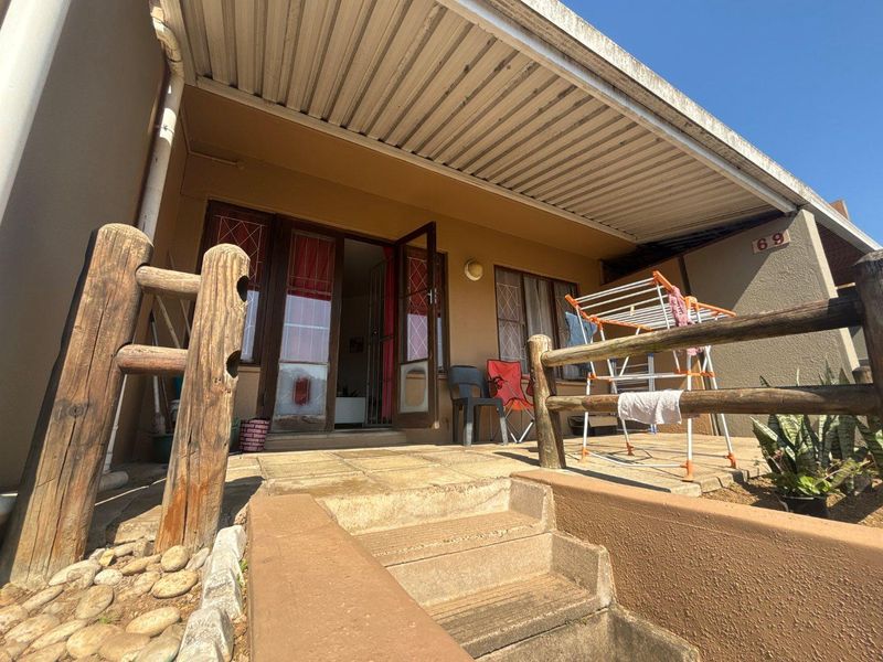 A covered outdoor patio area featuring concrete paving, timber railing, and direct access to the interior through a security gate.