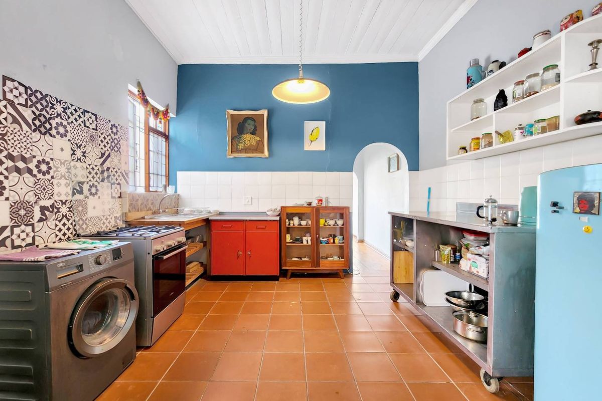 A characterful kitchen featuring tiled flooring, patterned splashback tiles, built-in shelving, and a freestanding stove, offering a unique and functional cooking space.