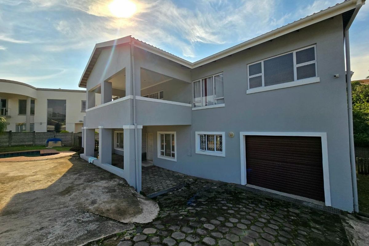 Rear view of a two-story house featuring a covered patio, integrated garage, paved driveway, and a swimming pool in the backyard.