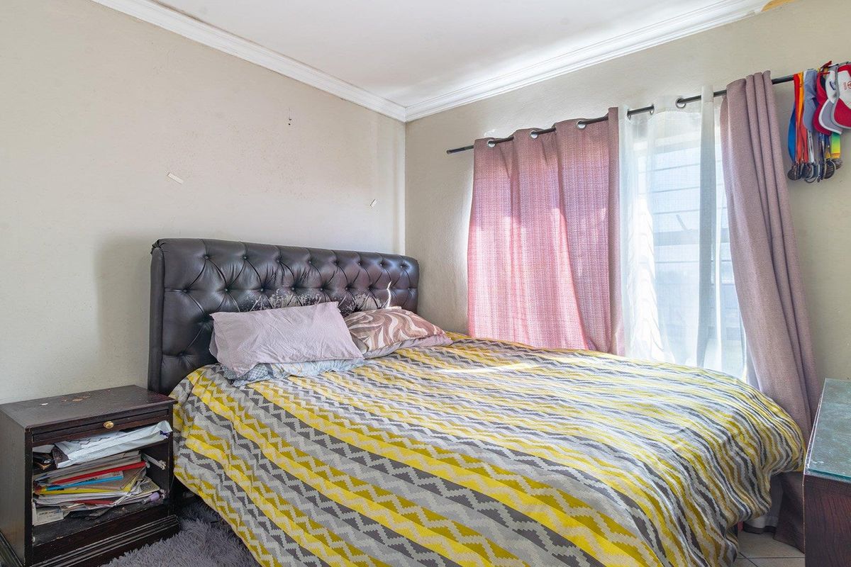 A standard bedroom featuring crown molding and a window with security bars, offering a functional space with potential for cosmetic updates.