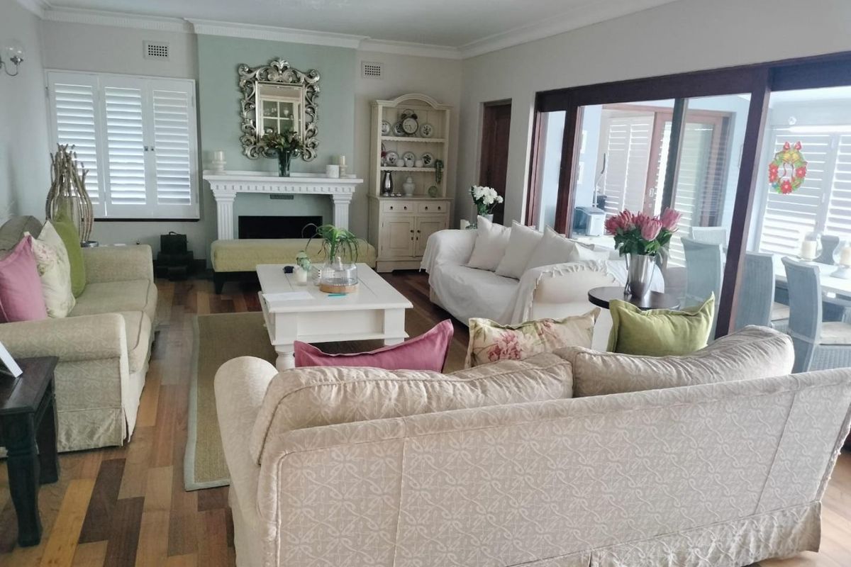 Spacious living room featuring timber flooring, a classic fireplace with mantelpiece, and large sliding glass doors providing access to the outdoor area.