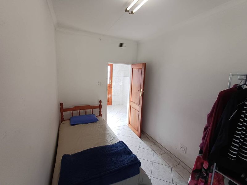 A compact bedroom featuring tiled flooring and a timber door leading to an adjacent space, providing a functional and simple living area.
