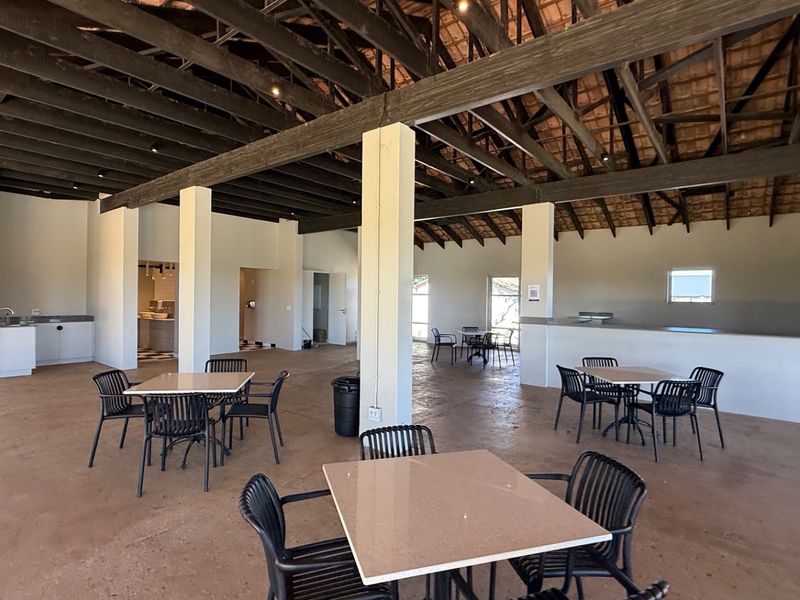 Spacious open-plan interior featuring exposed timber roof trusses, concrete flooring, and structural support columns, offering a versatile layout for various commercial or residential uses.