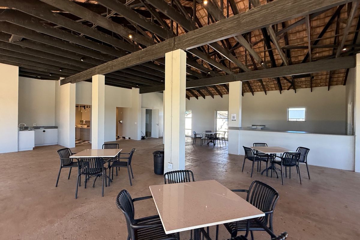 Spacious open-plan interior featuring exposed timber roof trusses, concrete flooring, and structural support columns, offering a versatile layout for various commercial or residential uses.