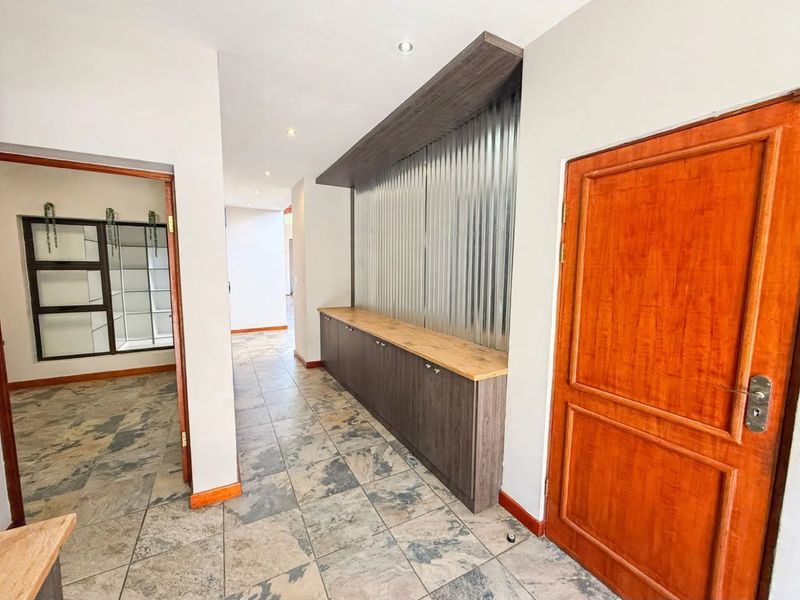 Spacious hallway featuring built-in cabinetry with a timber countertop, corrugated metal feature wall, and durable tiled flooring.