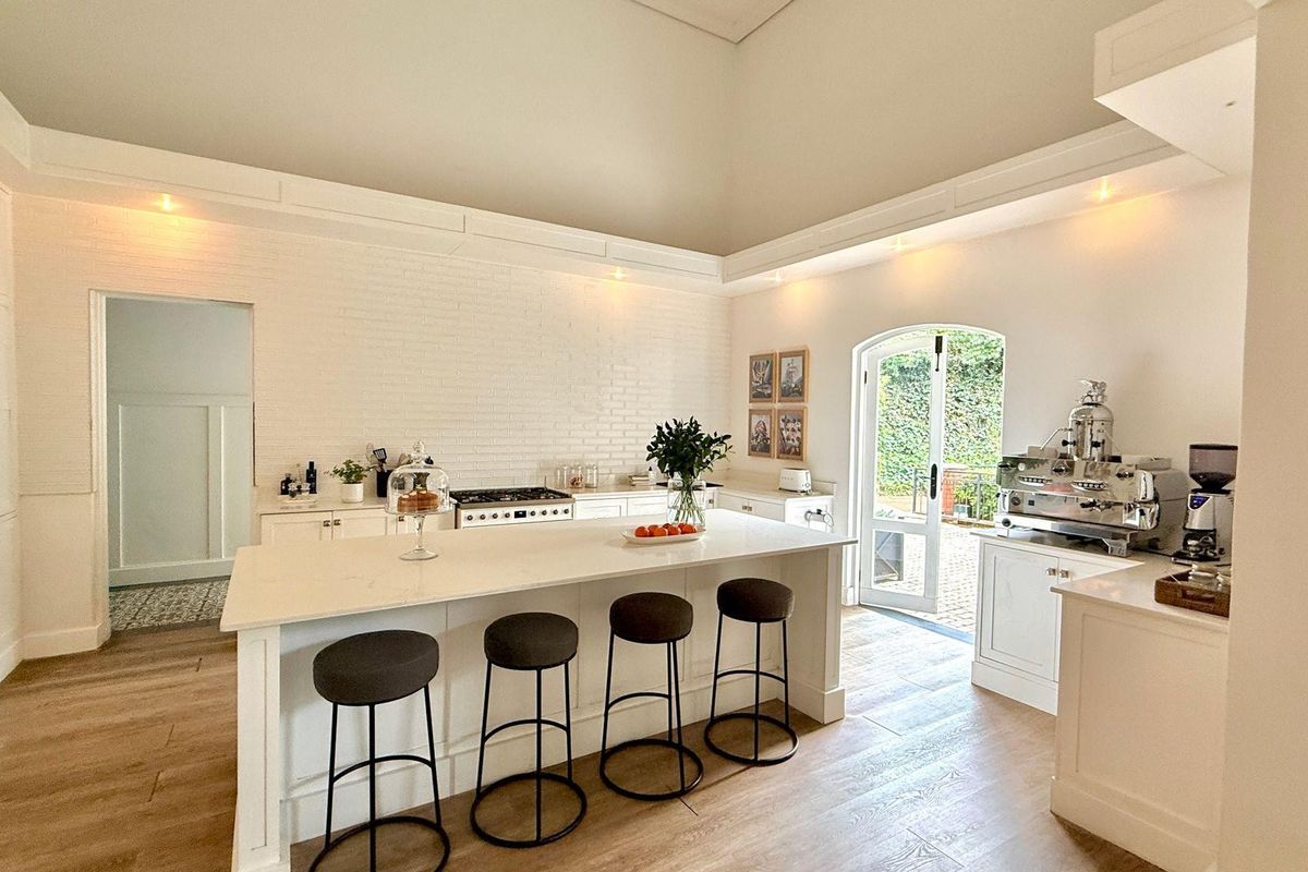 Bright and spacious kitchen featuring a large central island, built-in cabinetry, high ceilings, and direct access to the outdoor patio area.