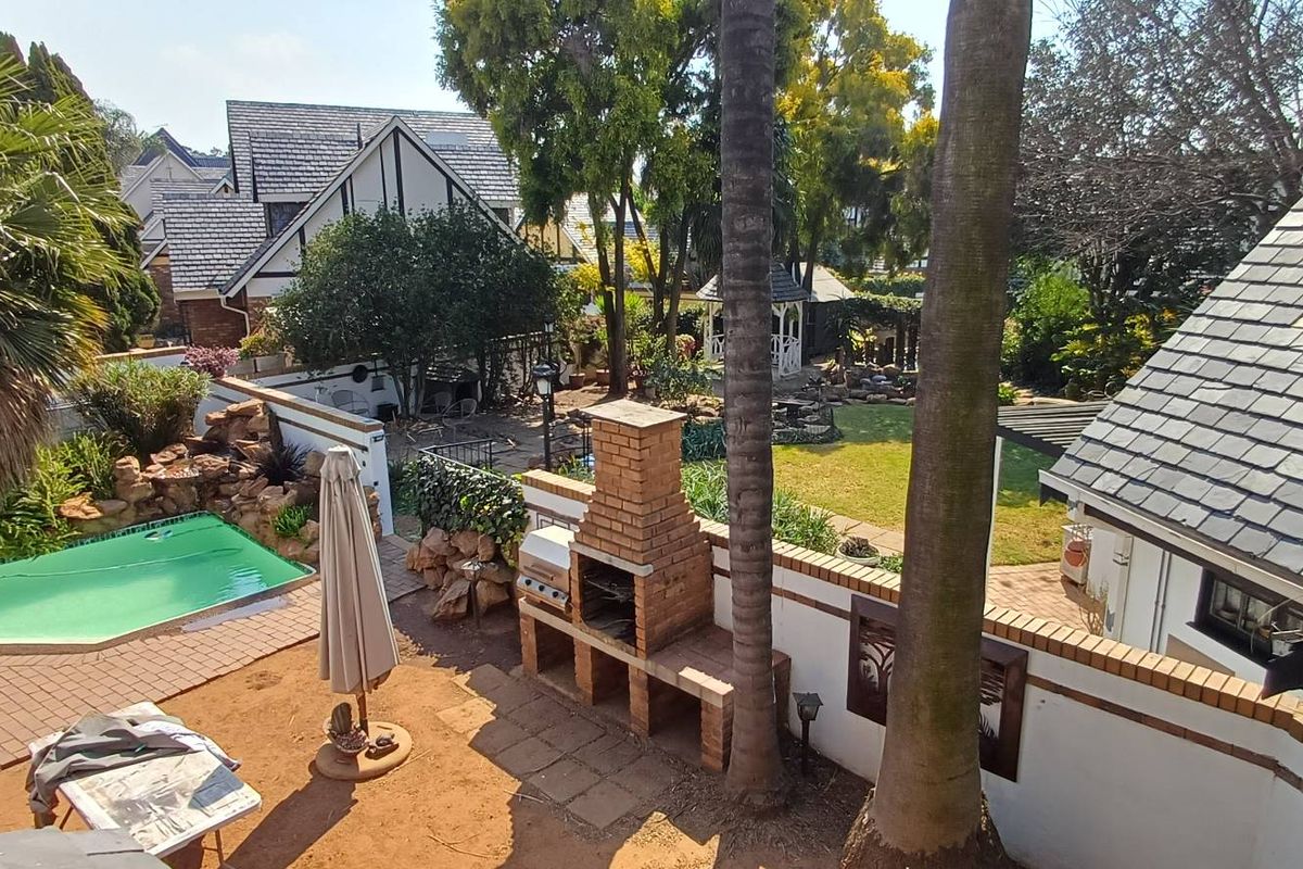 Spacious rear garden featuring a swimming pool, paved patio area, and a traditional brick built-in braai, perfect for outdoor entertaining.