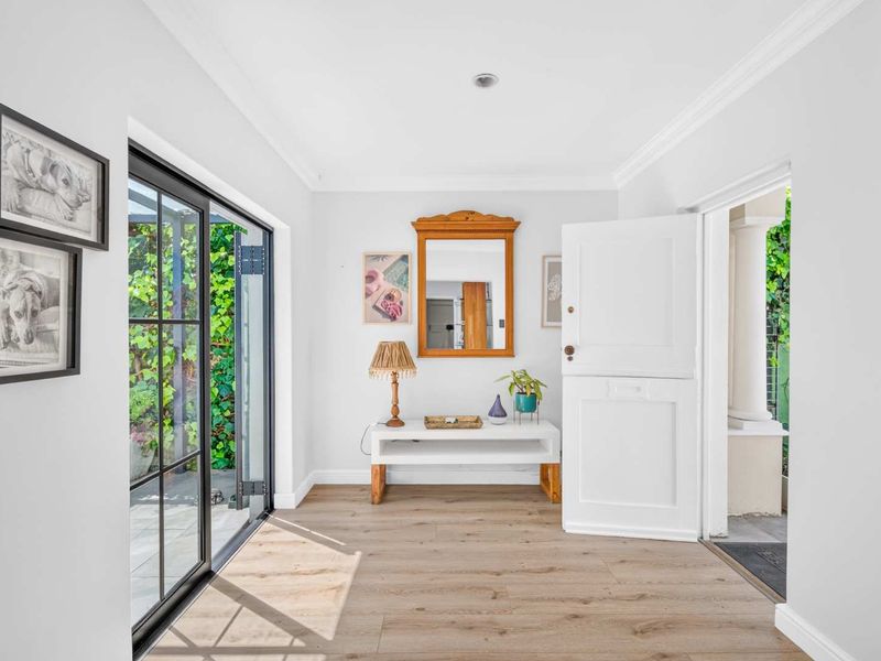 Bright and welcoming entrance hall featuring modern laminate flooring, a classic dutch door, and large glass sliding doors providing access to the garden.