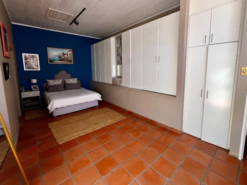 Spacious bedroom featuring terracotta tile flooring, timber panel ceiling, and extensive built-in cupboard storage.