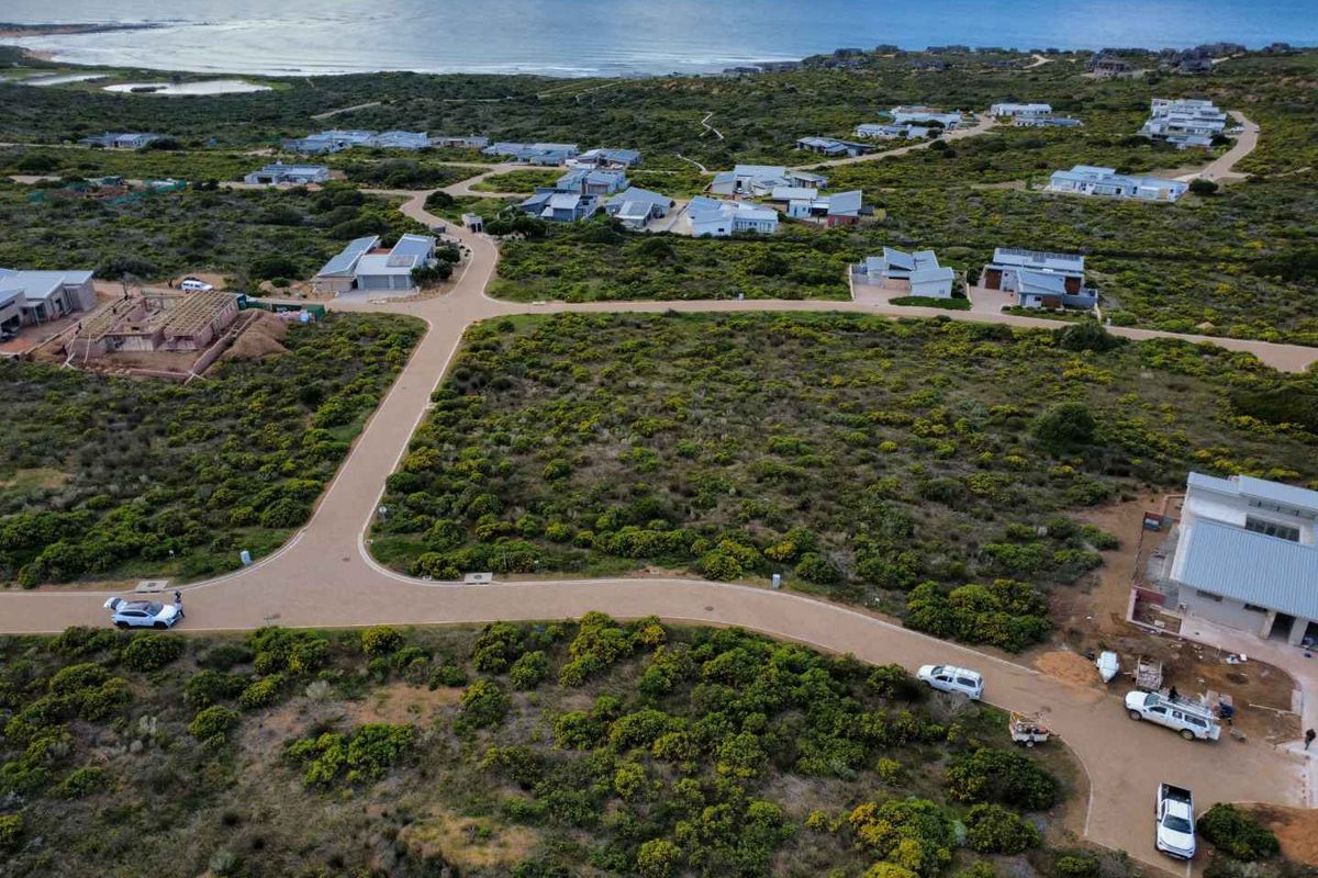 An aerial view of a coastal residential estate featuring paved roads and surrounding natural vegetation with ocean views.