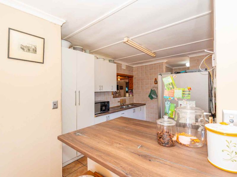 A functional kitchen featuring built-in cabinetry, a tiled backsplash, a stainless steel sink, and a breakfast bar area.