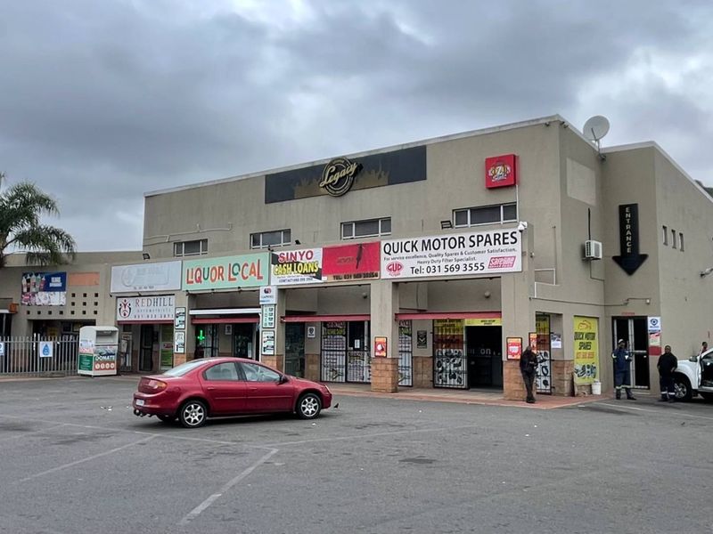 Front exterior view of a multi-tenant industrial and commercial retail complex featuring paved parking and various storefront signage.
