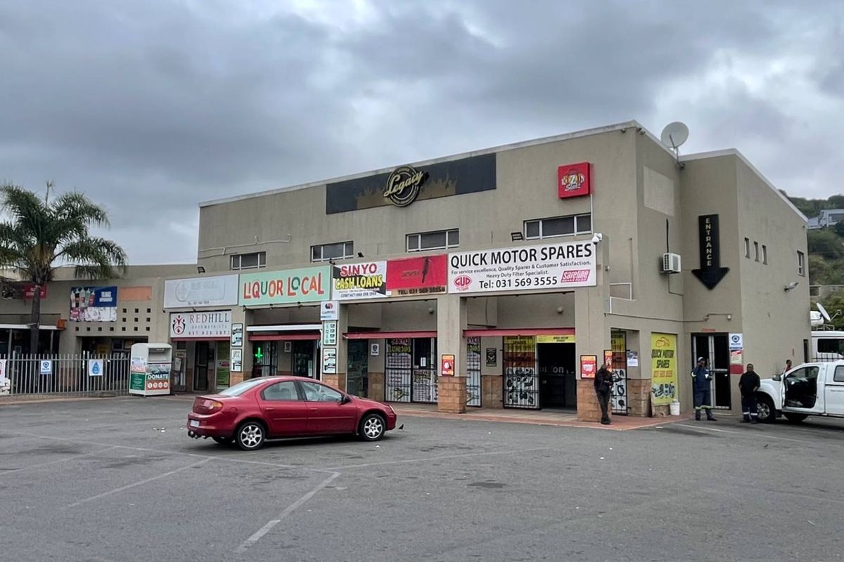 Front exterior view of a multi-tenant industrial and commercial retail complex featuring paved parking and various storefront signage.