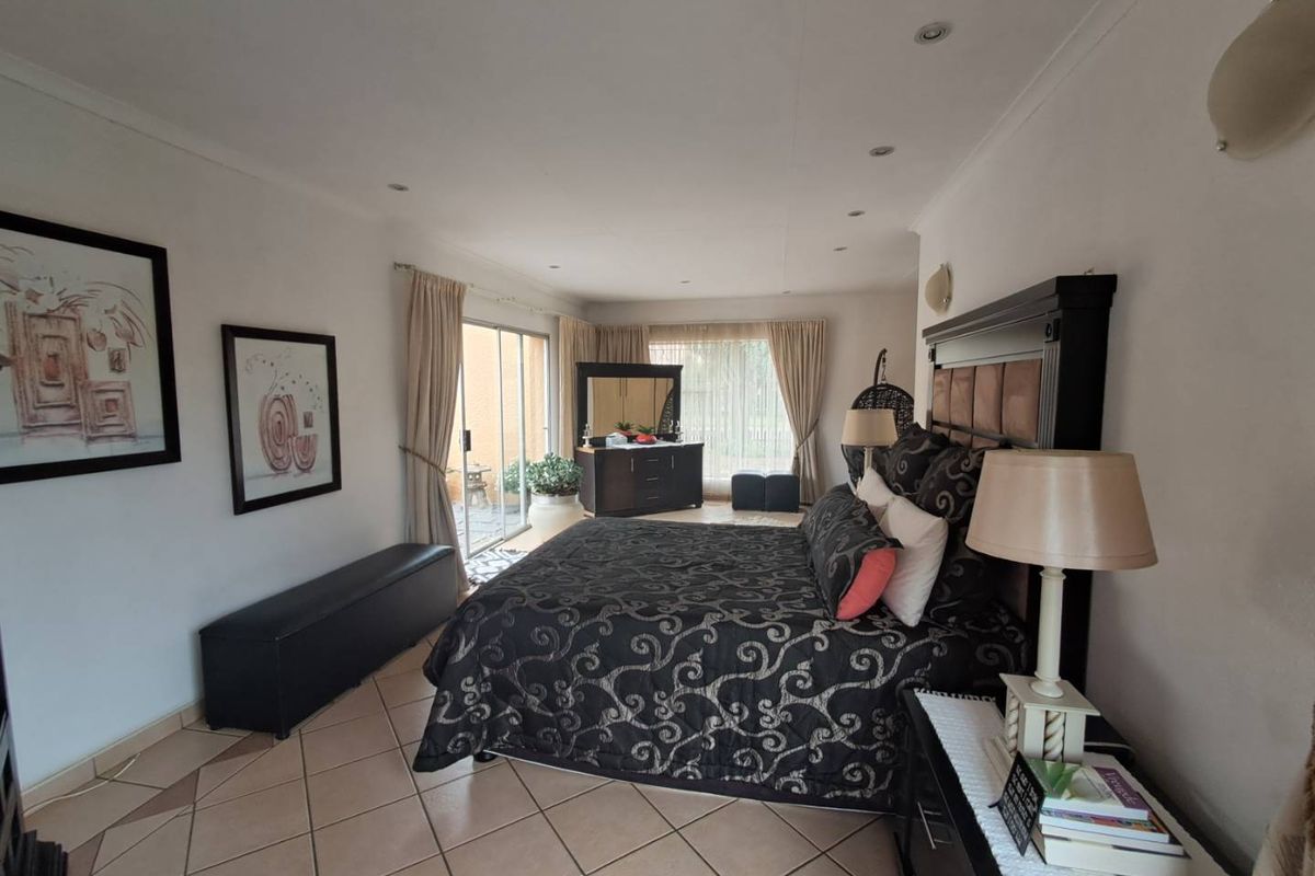 Spacious bedroom featuring tiled flooring, recessed ceiling lighting, and large sliding glass doors providing direct access to an outdoor patio area.