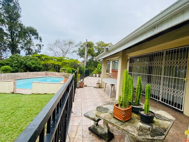 Covered patio area featuring tiled flooring and metal security gates, overlooking a private swimming pool and garden space.
