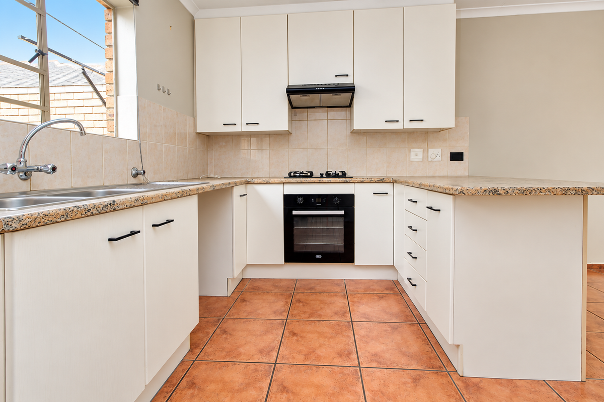 A functional kitchen featuring white cabinetry, granite countertops, a built-in oven with gas hob, and tiled flooring.
