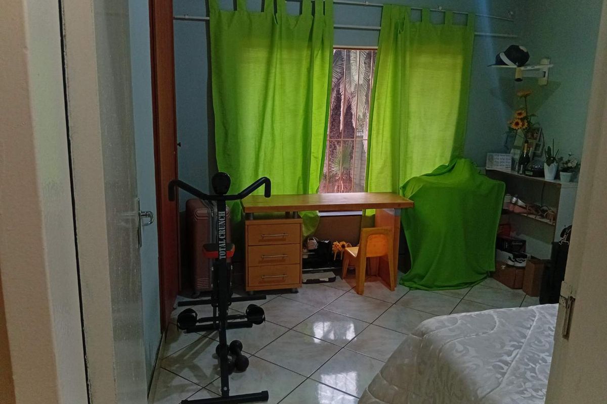 A bedroom featuring tiled flooring and a window with curtain rods, providing a functional space for rest or study.
