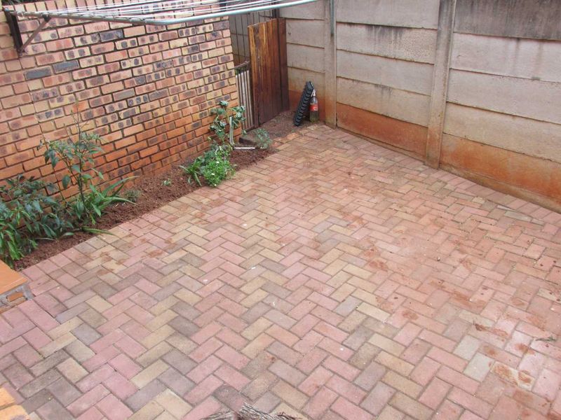 A private rear courtyard area featuring brick paving, enclosed by brick and precast concrete boundary walls with an installed washing line.