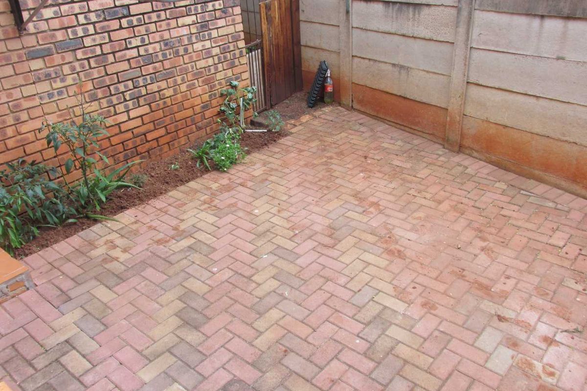 A private rear courtyard area featuring brick paving, enclosed by brick and precast concrete boundary walls with an installed washing line.