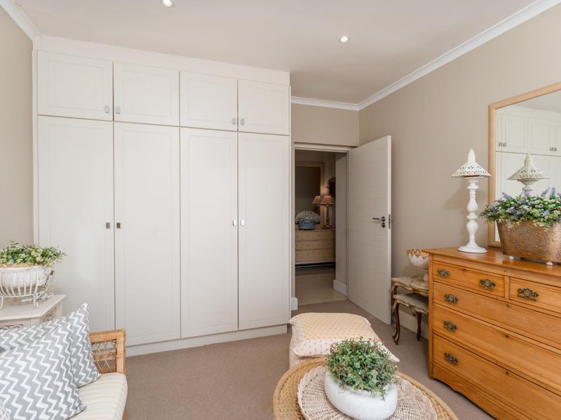 A well-maintained bedroom featuring neutral walls, carpeted flooring, and ample built-in cupboard storage with recessed ceiling lighting.