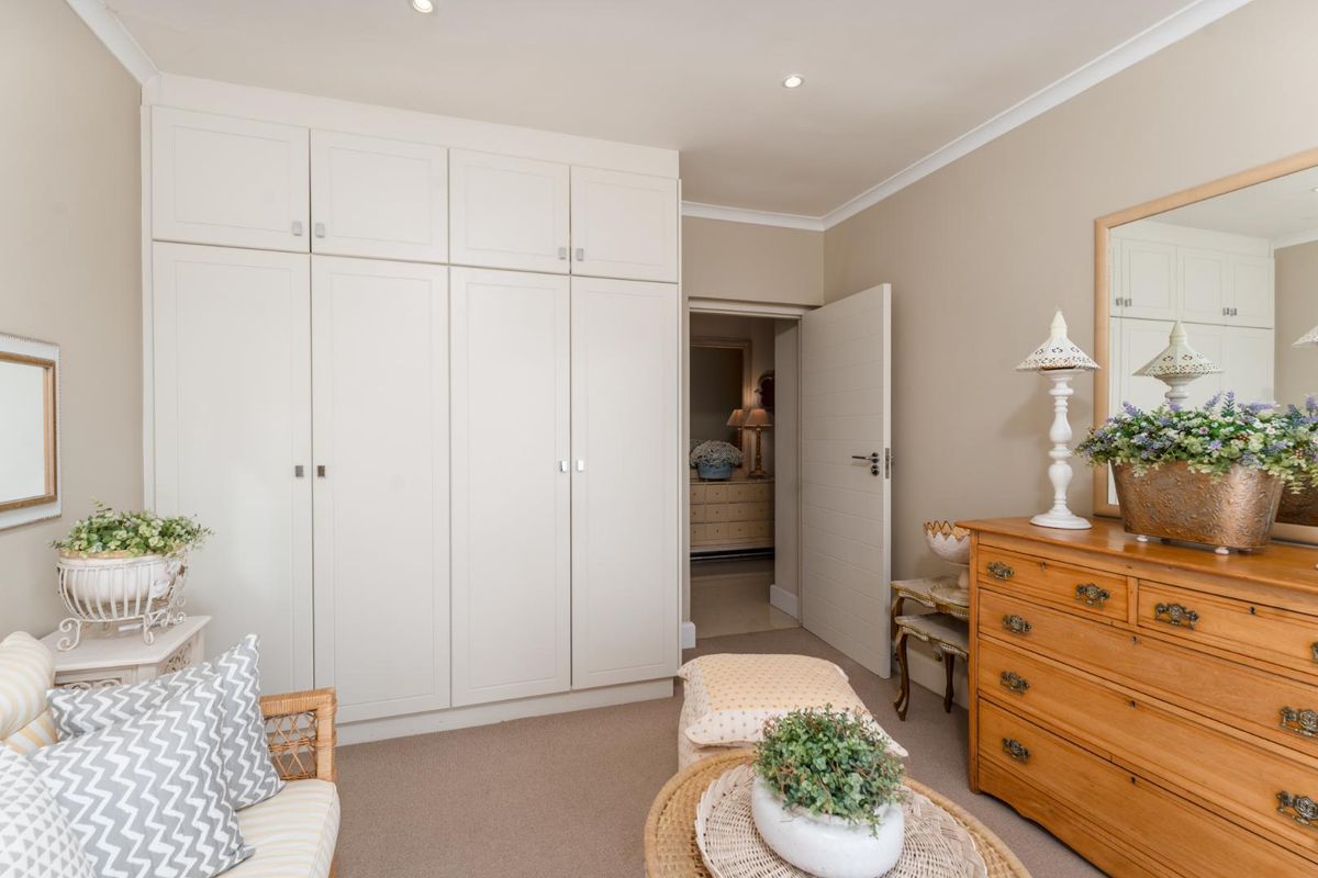 A well-maintained bedroom featuring neutral walls, carpeted flooring, and ample built-in cupboard storage with recessed ceiling lighting.