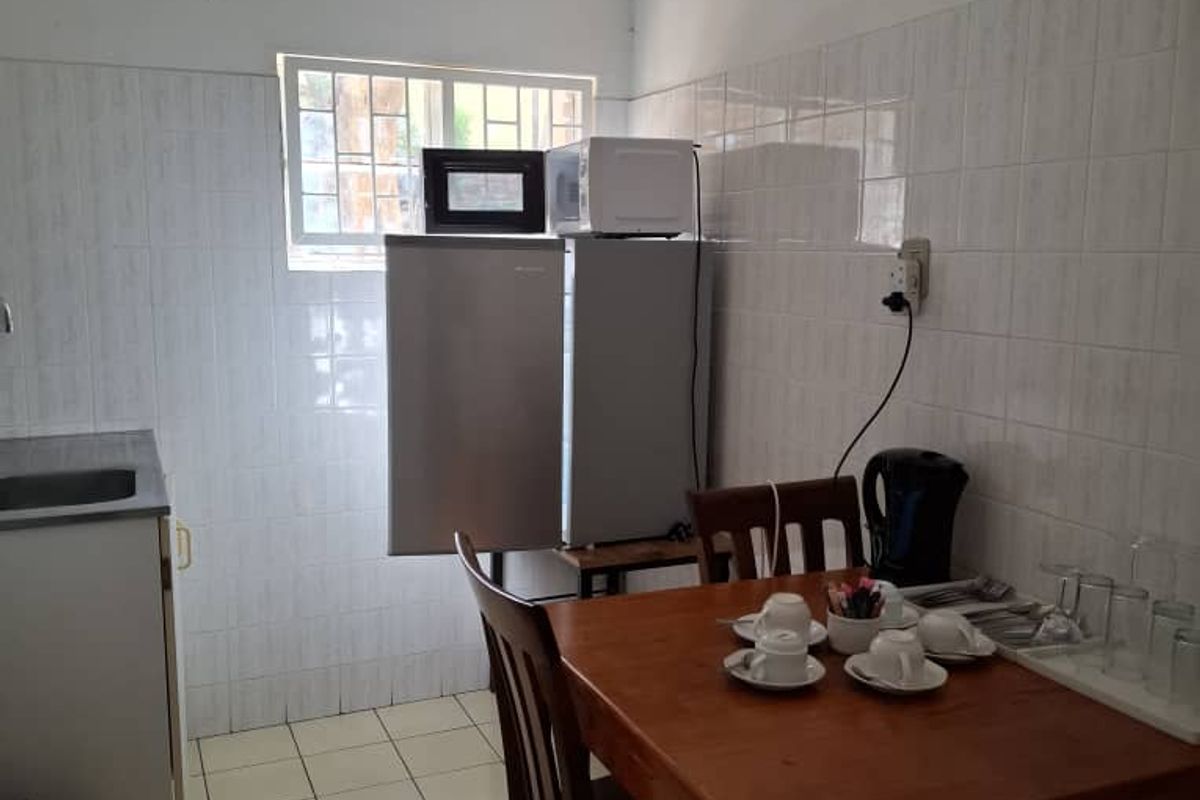 A compact kitchenette area featuring tiled walls, a small sink unit, and a dining space suitable for light meal preparation.
