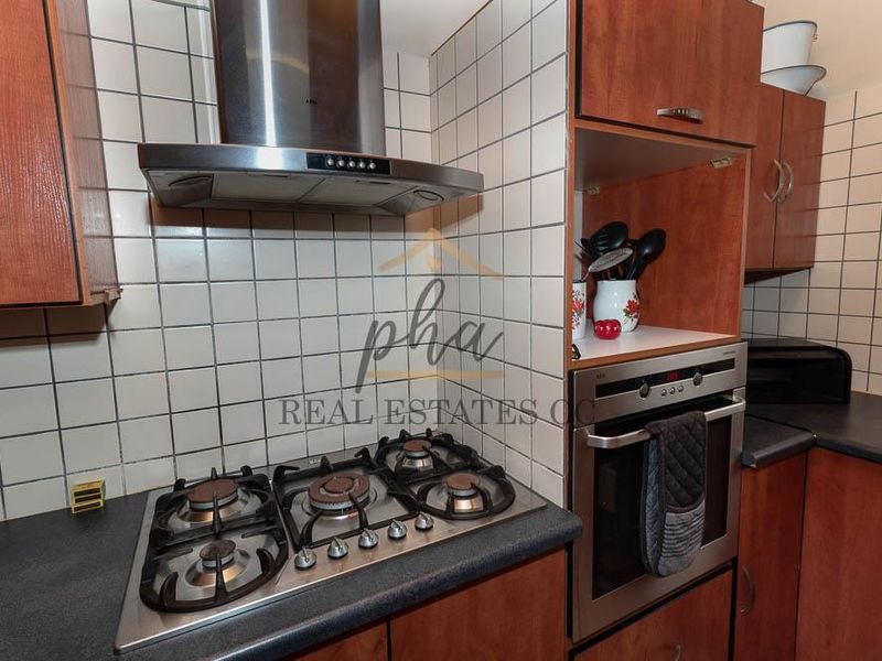 A functional kitchen featuring a gas cooktop, stainless steel extractor fan, built-in oven, and tiled backsplash with ample laminate cabinetry.