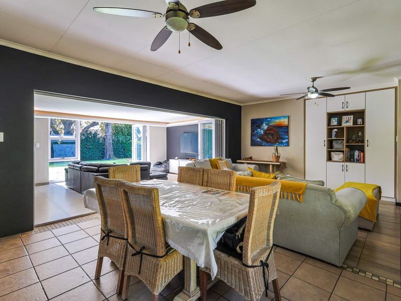 Spacious open-plan living and dining area featuring tiled flooring, ceiling fans, and large sliding doors opening to an outdoor patio space.