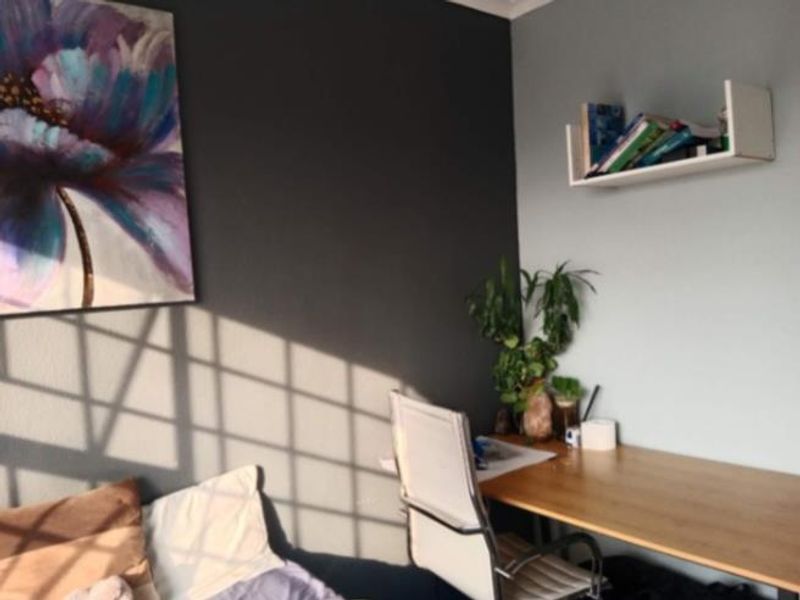 A bedroom featuring a functional workspace area with built-in shelving and a modern two-tone wall finish.