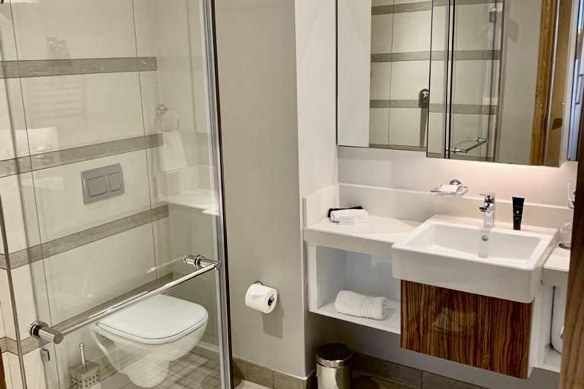 Modern bathroom featuring a glass-enclosed shower, wall-mounted toilet, and a contemporary vanity unit with integrated mirror storage.