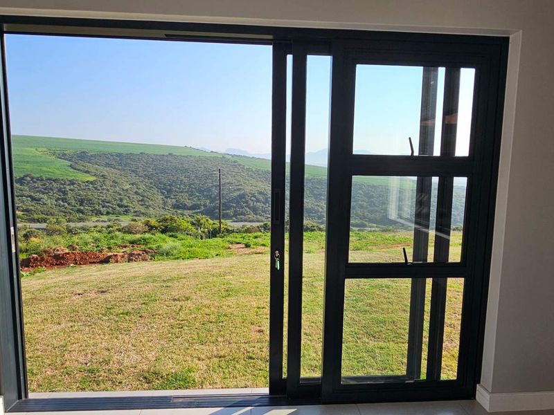 A view of the surrounding landscape and rolling hills captured through a modern sliding glass door.
