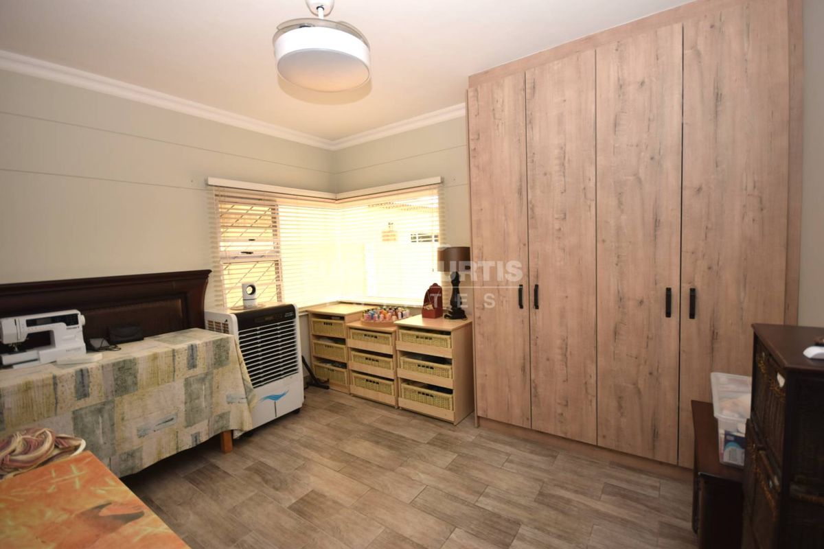 A well-maintained bedroom featuring modern wood-look floor tiles and extensive built-in cabinetry with a light wood finish.