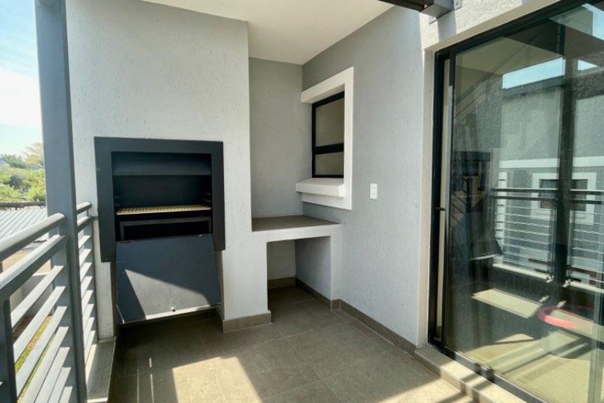 A covered balcony featuring a built-in braai, tiled flooring, and a modern pergola structure, providing an ideal space for outdoor entertaining.