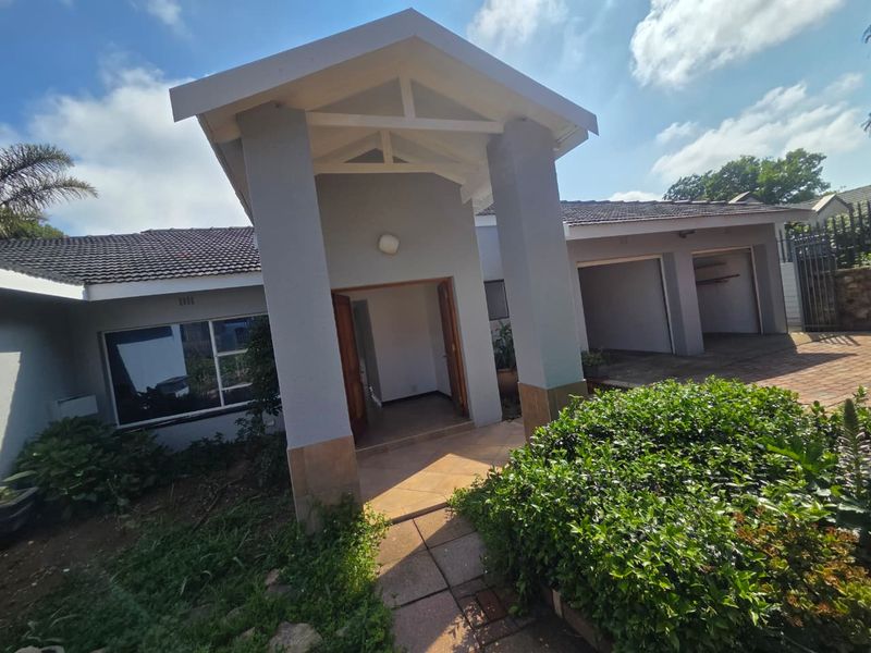 Front elevation of a house featuring a covered entrance, tiled roof, and a double garage with a paved driveway.