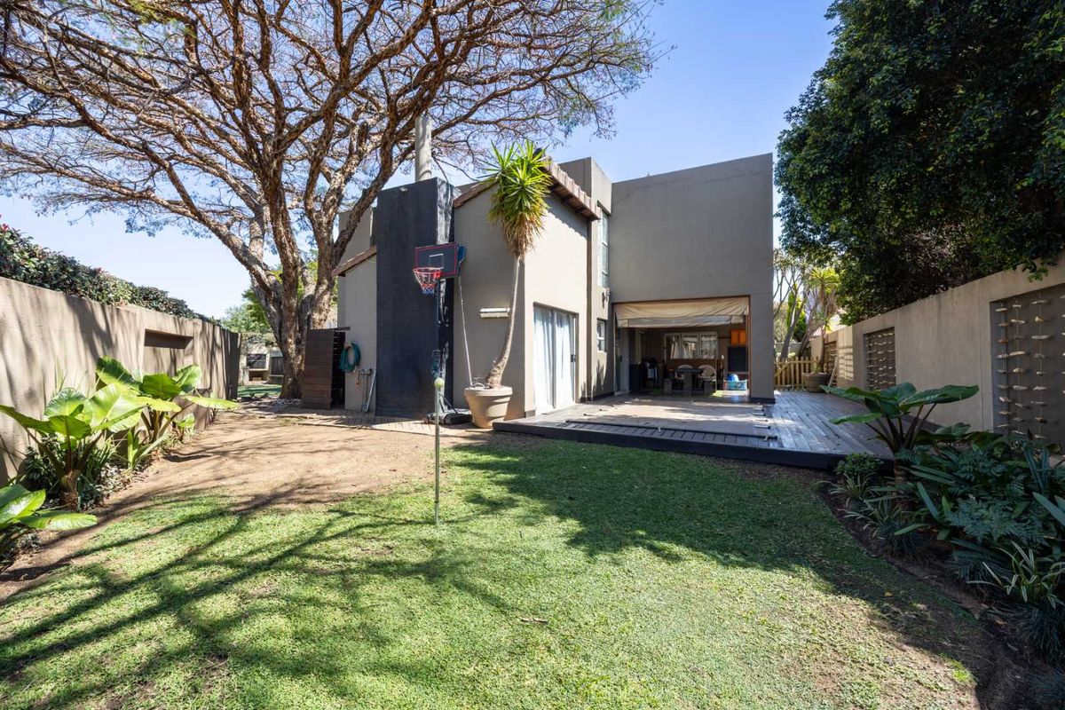 Rear view of the property featuring a wooden deck, sliding door access to the interior, and a private garden with a boundary wall.